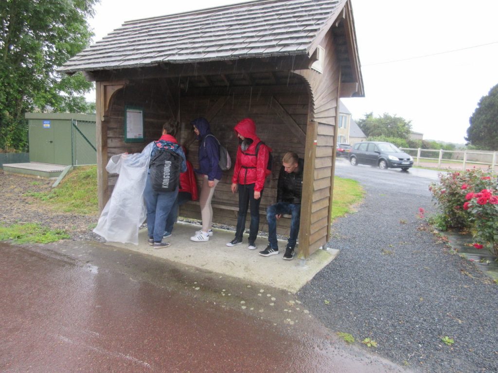 Surpris par la pluie diluvienne en pleine randonnée vers un Musée, le groupe trouve un peu de réconfort (et un lieu à sec ) sous un abribus.